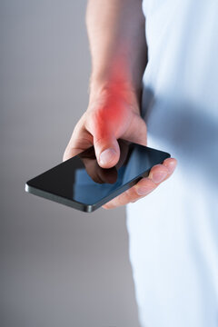 Pain in thumb use phone, close up hand with red backlight. Smartphone syndrome, gaming thumb and excessive screen time