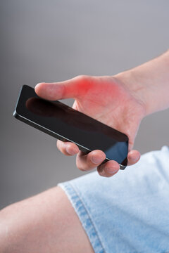 Pain in thumb use phone, close up hand with red backlight. Smartphone syndrome, gaming thumb and excessive screen time