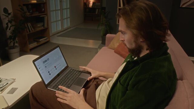 Caucasian young man watching bank account balance drop to zero on laptop with shocked expression. Perfect for cyber fraud, crypto loss, financial crisis and debt marketing