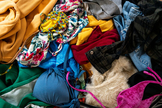 Heap of colorful mixed clothing and lingerie with bras, jeans and sweaters in a messy laundry pile