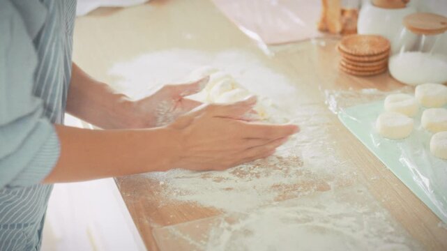 A woman works with soft cottage cheese dough on the kitchen counter, rolling and shaping it into portions. Concept of homemade cooking and traditional cottage cheese pancake recipe