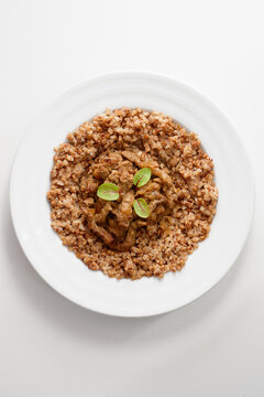 plated dish with toasted buckwheat groats surrounding tender seared meat slices, finished with bright green microgreens. Clean, white plate and minimal styling convey modern, rustic, healthy dining