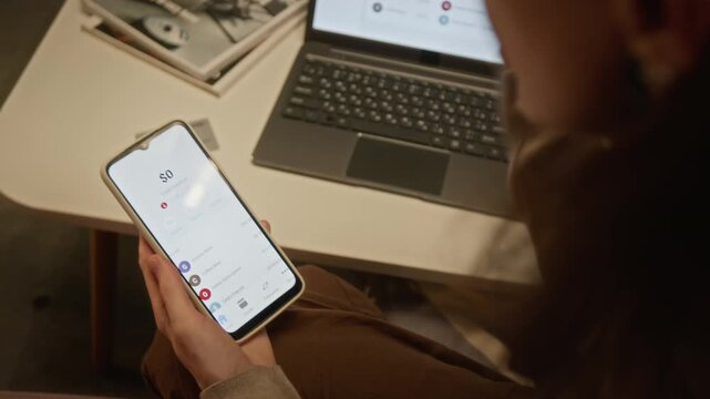 Unrecognizable woman watching bank account balance drop to zero on smartphone while gesturing emotionally. Ideal for cybersecurity, financial loss, banking crisis, and fraud prevention videos