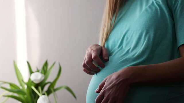 Pregnant woman scratching and after gently petting her big belly. Skin stretching during pregnancy. 4K