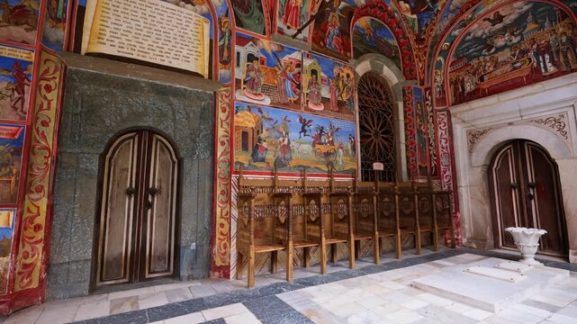 Interior gallery Rila Monastery with colorful orthodox frescoes and wooden seats UNESCO world heritage historic landmark in Bulgaria travel video stock