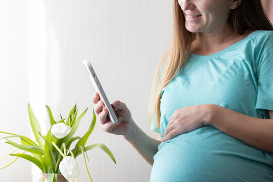 Smiling pregnant woman with smartphone.