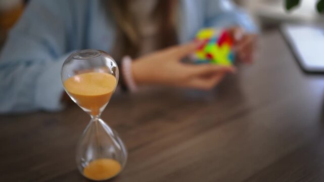 Young girl engaging with educational puzzle while hourglass counts down, representing learning through play, child development, cognitive skills, focus and creativity