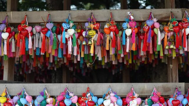Many colorful hear-shaped Chinese style amulets with writings hanging in wooden shrine at Yun Lai in Thailand, tourists and locals hang hearts with wishes for wealth, health, declarations of love.