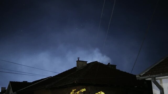 A cloudy night sky with a house in the background