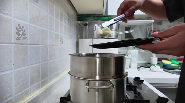 만두를 찜통에서 접시에 담는 한국주방의모습