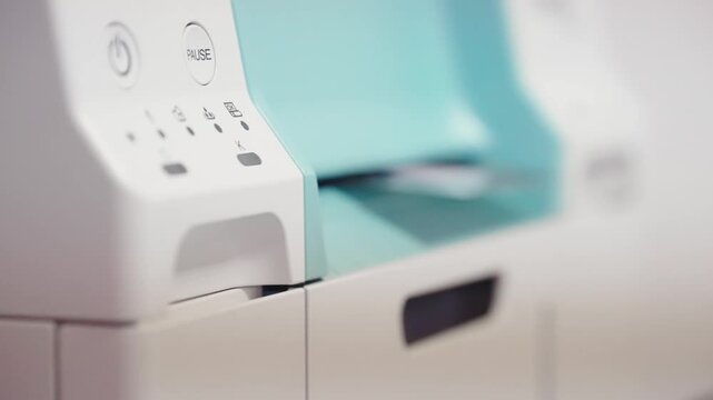 A white and blue printer with a green handle. The buttons on the printer are labeled "Print," "Pause,"