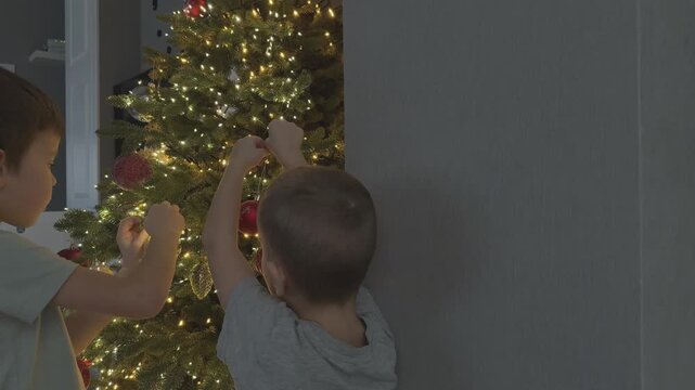 Small boy reaching to hang ornament on Christmas tree. Emotional childhood moment. Perfect for parenting and holiday marketing.