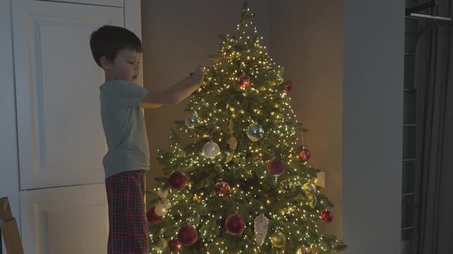Close up of child hands placing ornament on Christmas tree. Focus on detail and festive activity. Perfect for holiday marketing and family content.