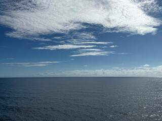 Obraz premium Ocean blue glittering waters and blue sky with beautiful white clouds 