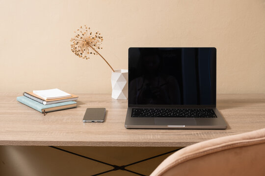 Desk setup with laptop, phone, and notebooks in a simple indoor space