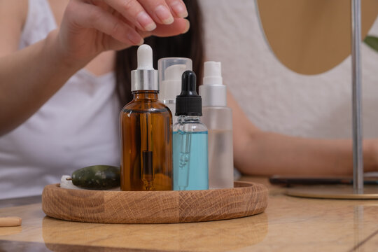 Person interacting with skincare products on a wooden tray in a light space during the day
