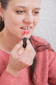 Woman applies lipstick in a casual indoor setting during daytime
