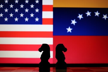United States and Venezuela flags behind chess knight pieces. Oil negotiations, economic sanctions, and geopolitical relations concept. © Blossom Stock Studio