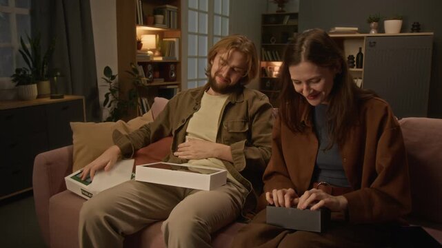 Caucasian young couple unboxing tablet and smartphone happily at home. Footage suitable for consumer electronics advertising, retail promos and e-commerce campaigns