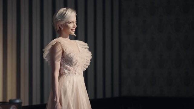 Happy smiling elegant fashion woman in a bride dress stands in front of a wall