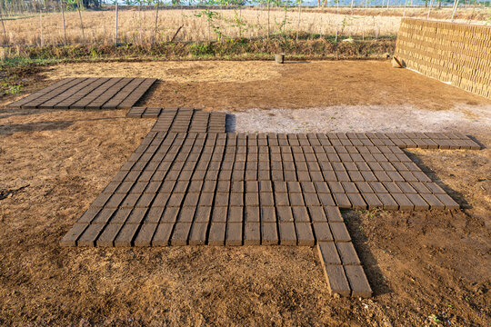 Rows of raw handmade clay bricks drying under the sun in rural brickyard