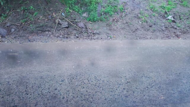 Heavy rain falls outside a window as muddy floodwater flows across the landscape