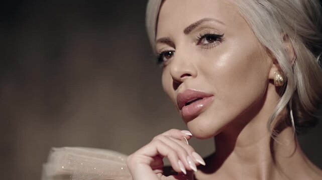 Bride woman touching tenderly her face showing a concept of skin care, wearing dress with a pearl necklace and earrings, slow motion cinematic shot
