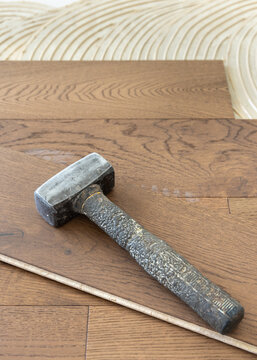 Rubber mallet on brown oak parquet planks during hardwood flooring installation closeup