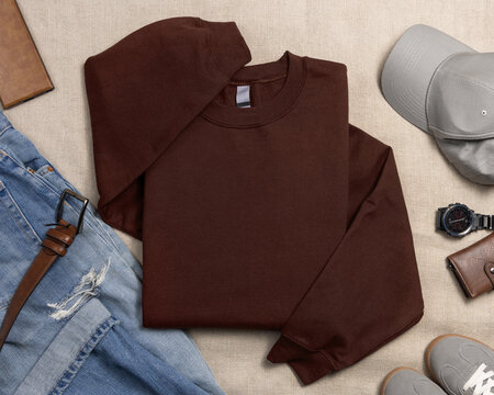 Blank brown unisex sweatshirt mockup, folded crewneck with mens accessories and sneakers