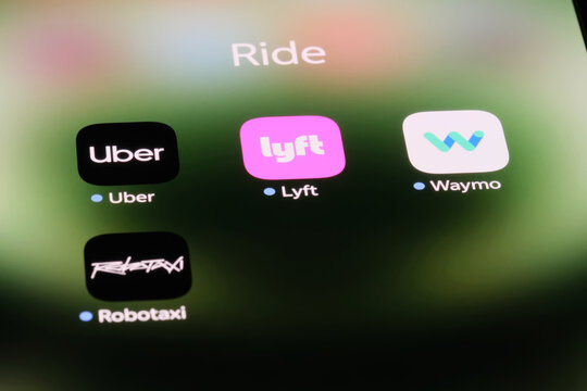 Shanghai,China-Sep.6th 2026: ride-hailing and autonomous driving app icons including Uber, Lyft, Waymo, and Tesla Robotaxi displayed on a smartphone screen