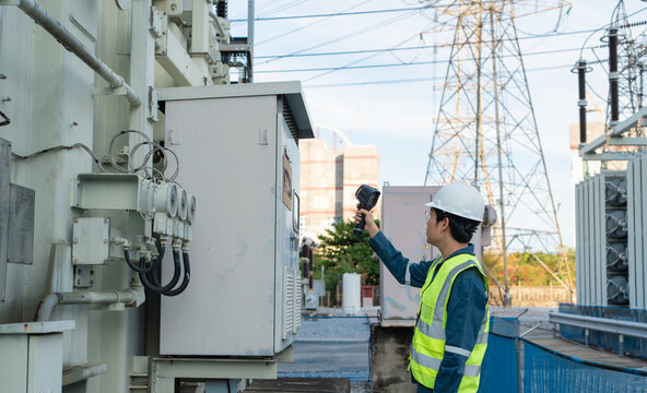Industrial monitoring with a thermal camera helps an engineer inspect transformer equipment and cabinet connections in a high voltage substation for safety and condition checks.