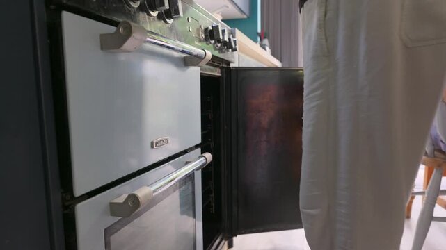 4K video of a person wearing an oven mitt closing a kitchen oven door.