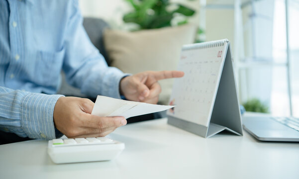 Business professional holding receipts and pointing at calendar for tax deadline planning bill payment scheduling expense tracking budgeting cash flow control and financial management.