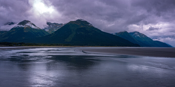 Alaska autumn coastal seascape along the Turnagain Arm at sunset with purple clouds and wet sand reflection at low tide