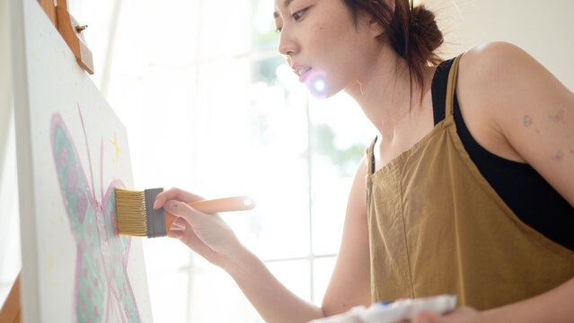 Woman Painting on a Canvas in a Bright Room With Large Windows