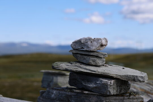 Stone cairn in focus on the alpine plateau at Flatruet with mountains in the background on a sunny summer day