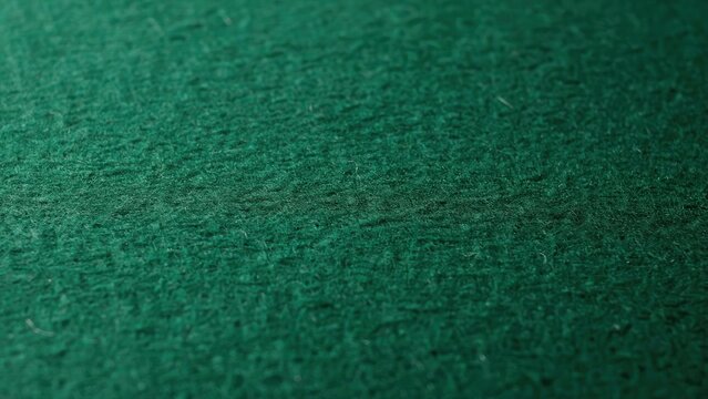 Close-up of textured green felt fabric on a casino table with soft lighting. Ideal background for gambling or sports betting ads.