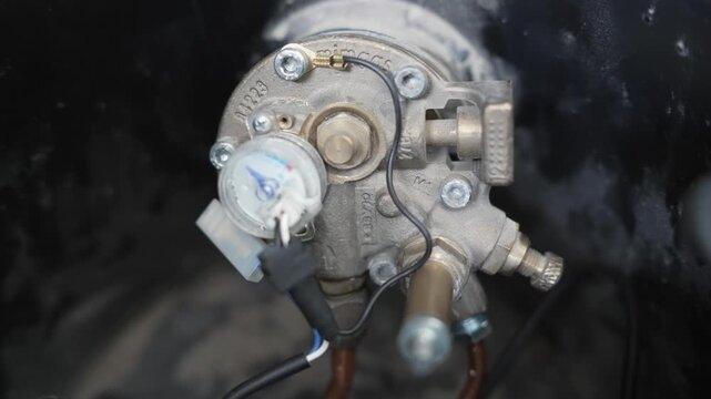 A small car lpg tank measurement gauge is attached to a piece of equipment. The gauge is black and white