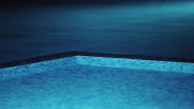 Illuminated swimming pool with a blue tile border and a blue water surface, night shot. The water is calm and still