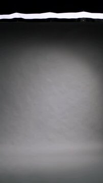 Vertical video: Shifting LED strip causing gray roll brightening into circular patch at studio
