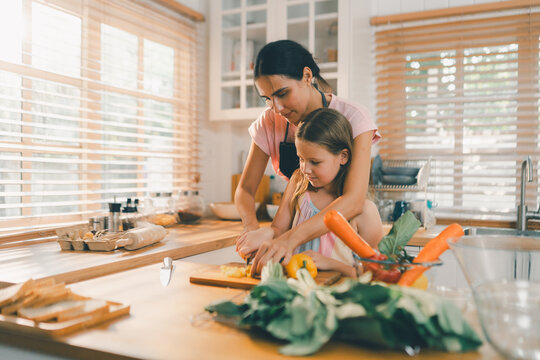 Family cooking concept with parents and daughter preparing homemade food together in a bright kitchen, sharing baking skills and quality time. family, cooking, kitchen, baking, together