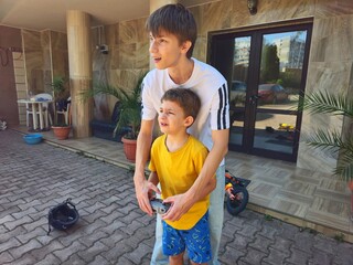 Little boy with his brother operating a drone using a remote controller and joystick in the yard during summer © Татьяна Швец