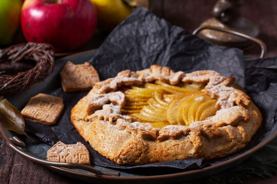 Apple galette, gingerbread houses, and apples on a wooden background.