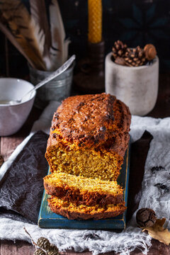 Pumpkin raisin bread with icing, served with tea on a dark background. Halloween concept.