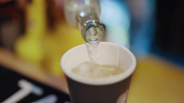 A bottle of brandy is poured into a cup, the cup is half full