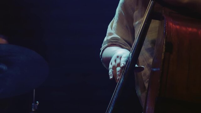 A man playing a contrabass with his hand in slow motion. Concept of calm and focus as the musician plays his instrument