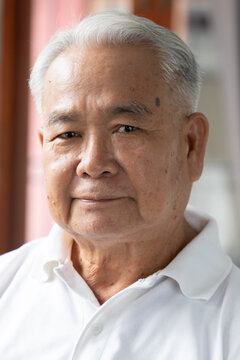 southeast asian senior man face portrait with neutral mood and emotionless expression, indoor scene