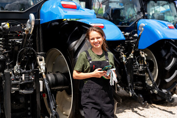 Portrait of a female mechanic standing in front of tractors outdoors © Igor Barilo