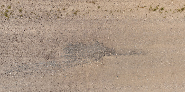 view from above on texture of gravel road among grass field