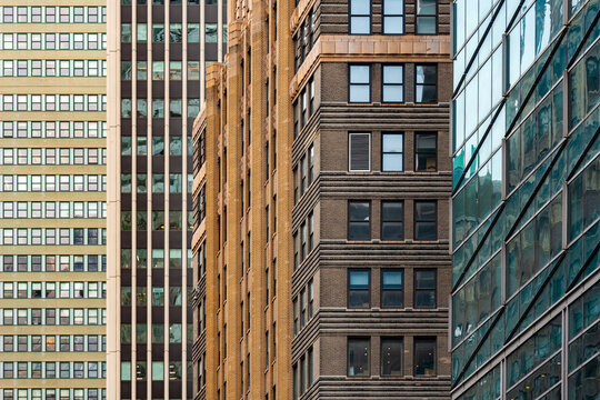 Geometric textures and architectural patterns of historic brick and modern glass buildings create a layered visual design across skyscraper facades in Manhattan, New York.
